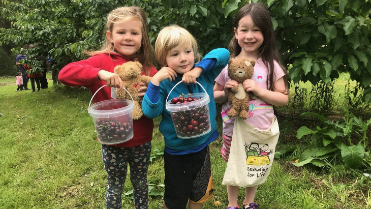 Children holding buckets of cherries